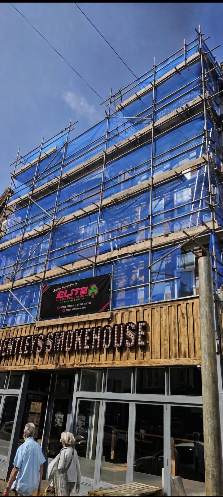 Blue debris netting and an Elite banner above Bentley's Smokehouse