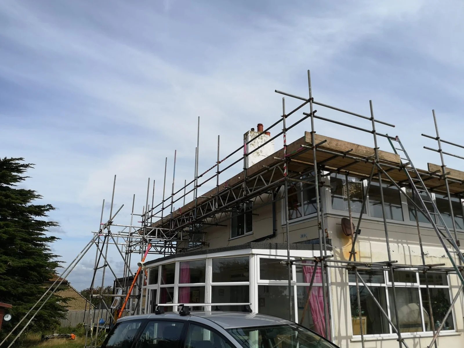 Scaffold spanning over a conservatory to a house roof